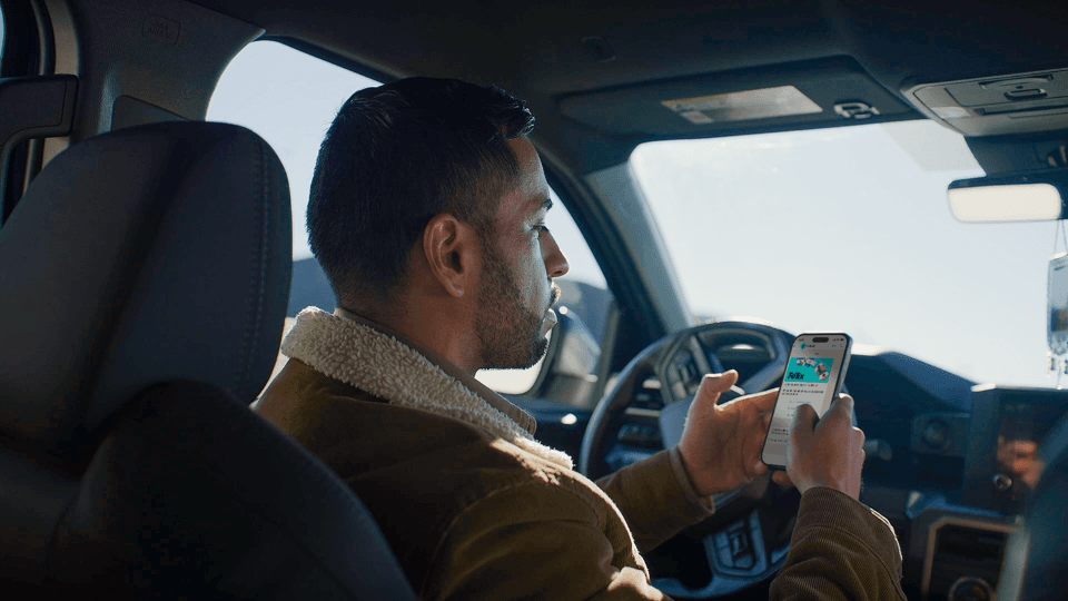 Hombre consulta su teléfono móvil sentado al volante de un vehículo