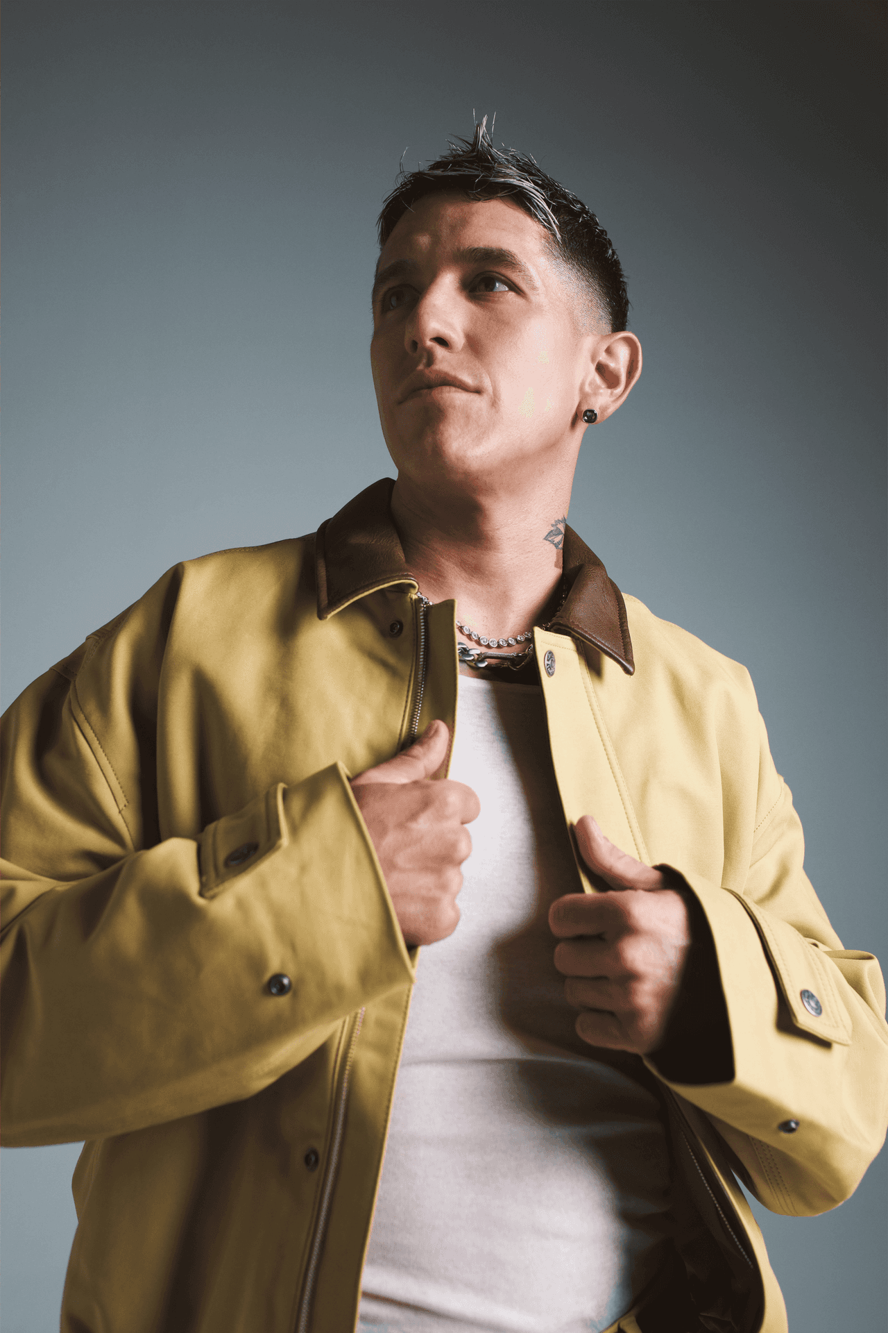 Lenny Tavárez con chaqueta color mostaza y camiseta blanca