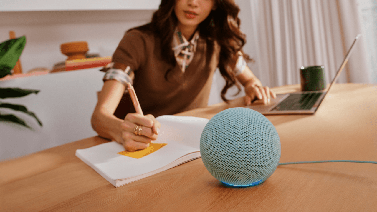 Una persona trabaja en su escritorio junto a la laptop, una libreta y el nuevo Echo Dot