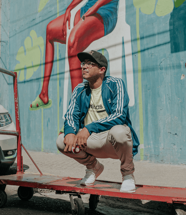 El muralista dominicano Angurria posa frente a uno de sus murales