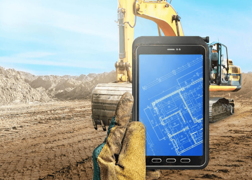 Una mano con guante sostiene una tableta Galaxy Tab Active con planos en una obra de construcción